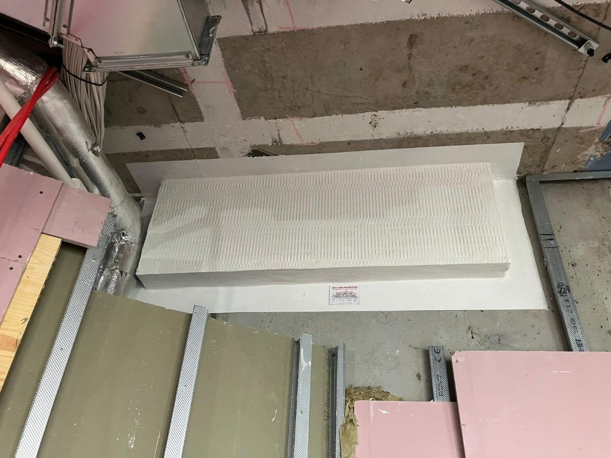 White ablative-coated batt installed on a wall with construction materials nearby.