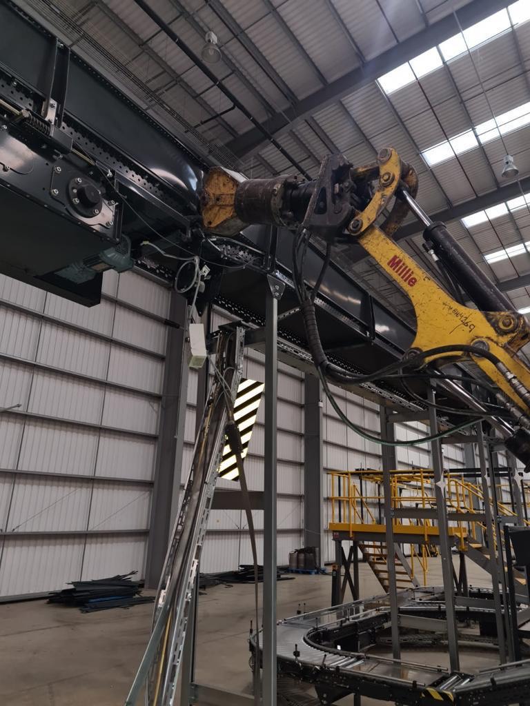 Yellow industrial robotic arm working inside a large factory building.