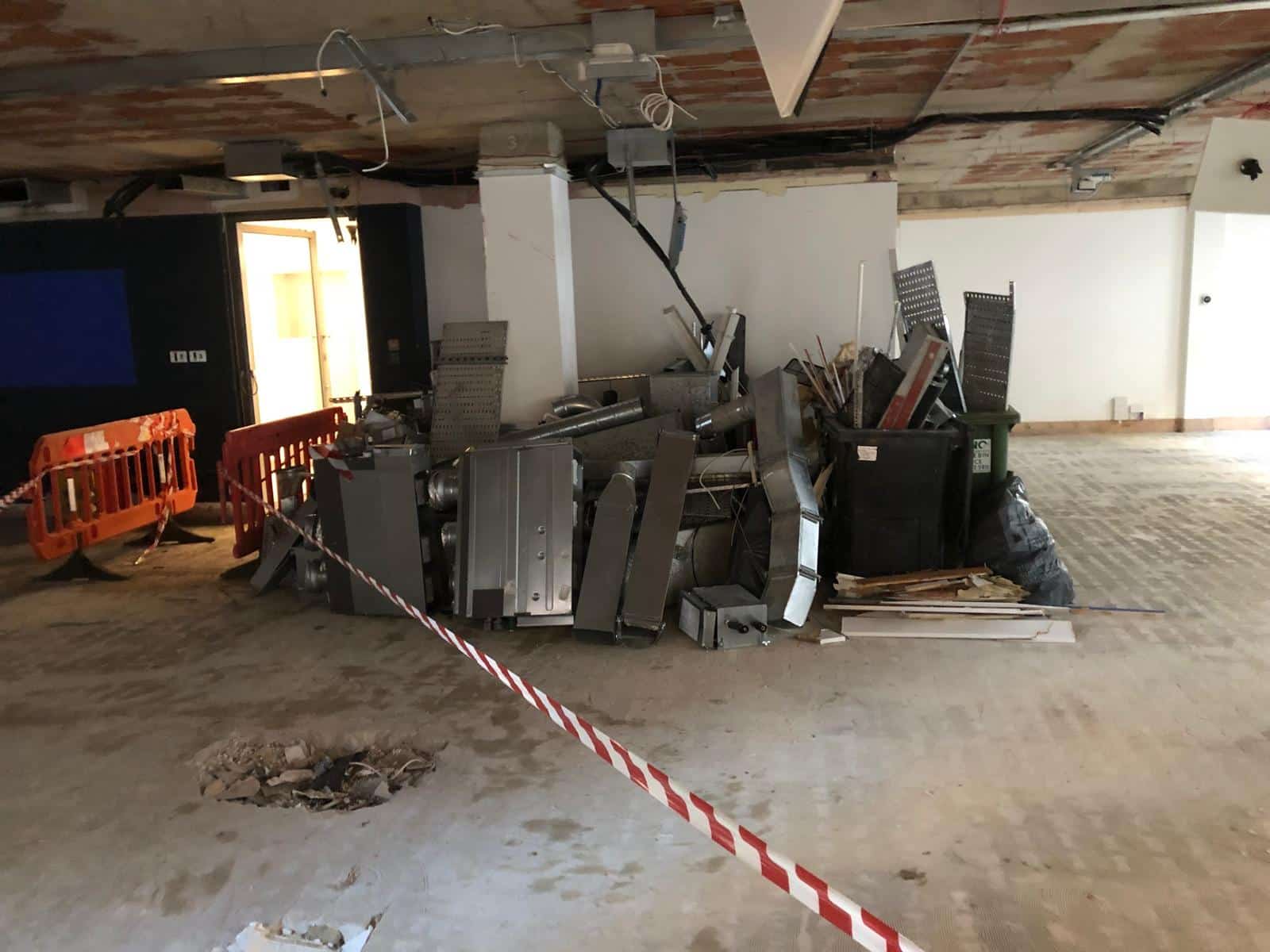 Piles of construction debris and metal pieces inside a partially renovated building.