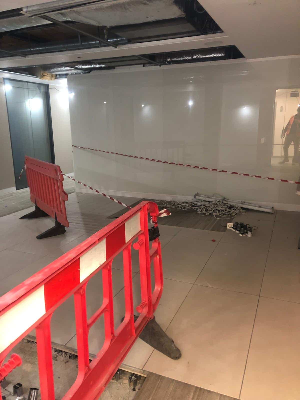 Red barriers and caution tape block off a construction area inside a building.