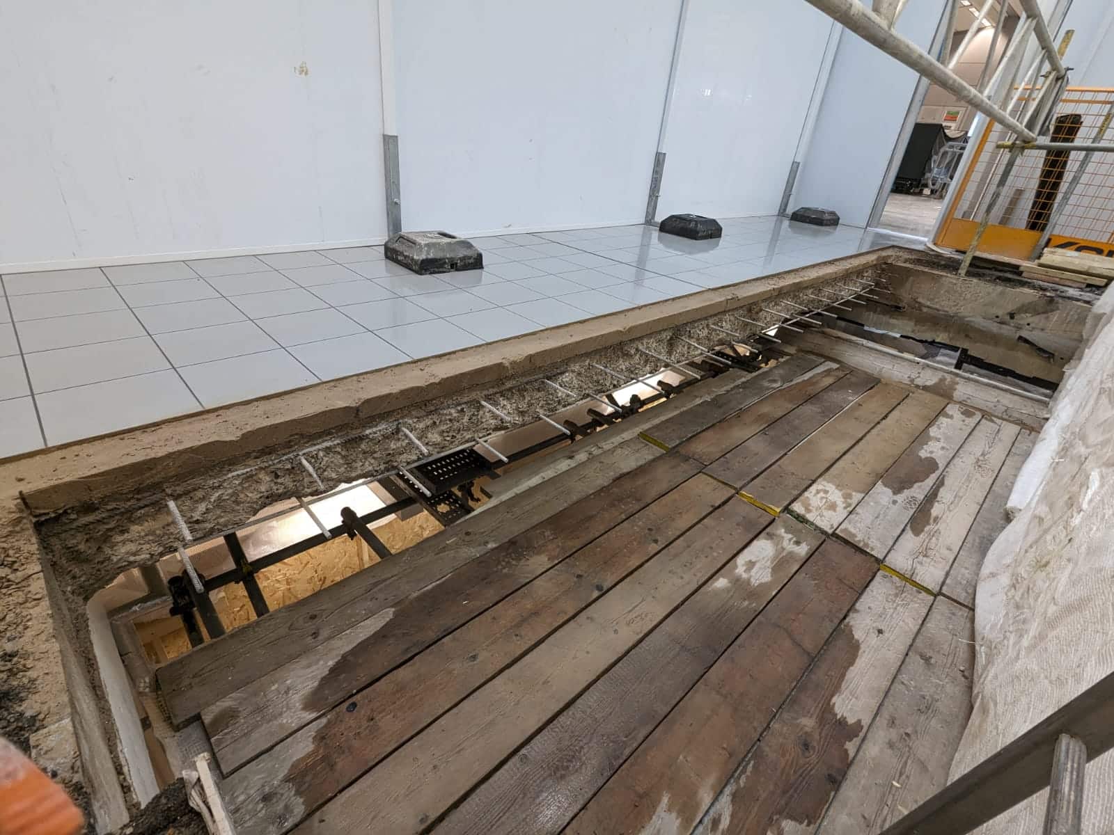 Wooden floor with missing and damaged boards, exposing the subfloor and area beneath.