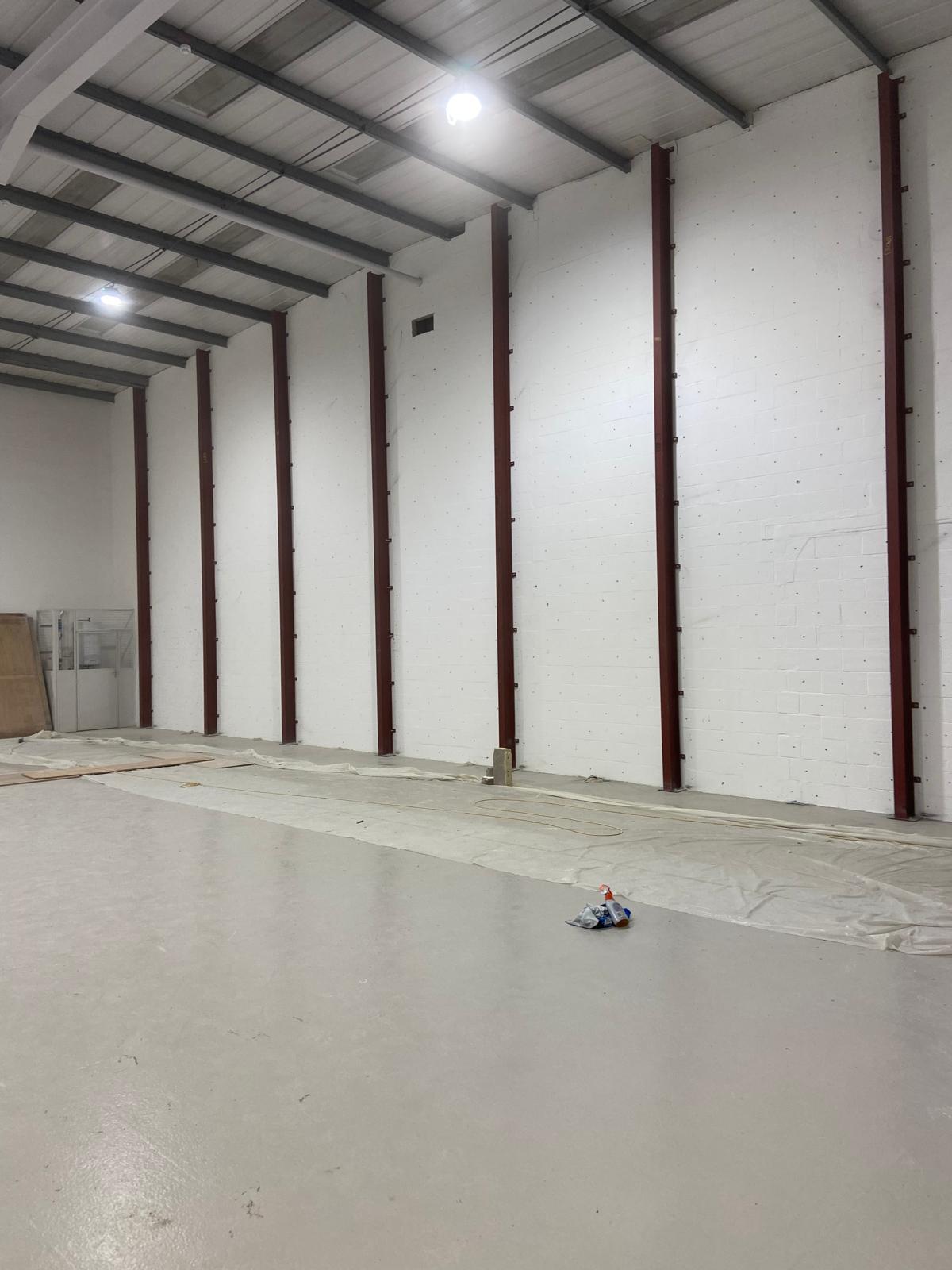 Interior of an empty warehouse with white walls and exposed steel beams.