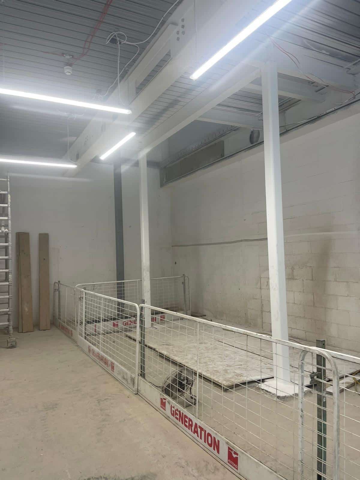 White steel beams in an indoor construction site, fenced off for safety.